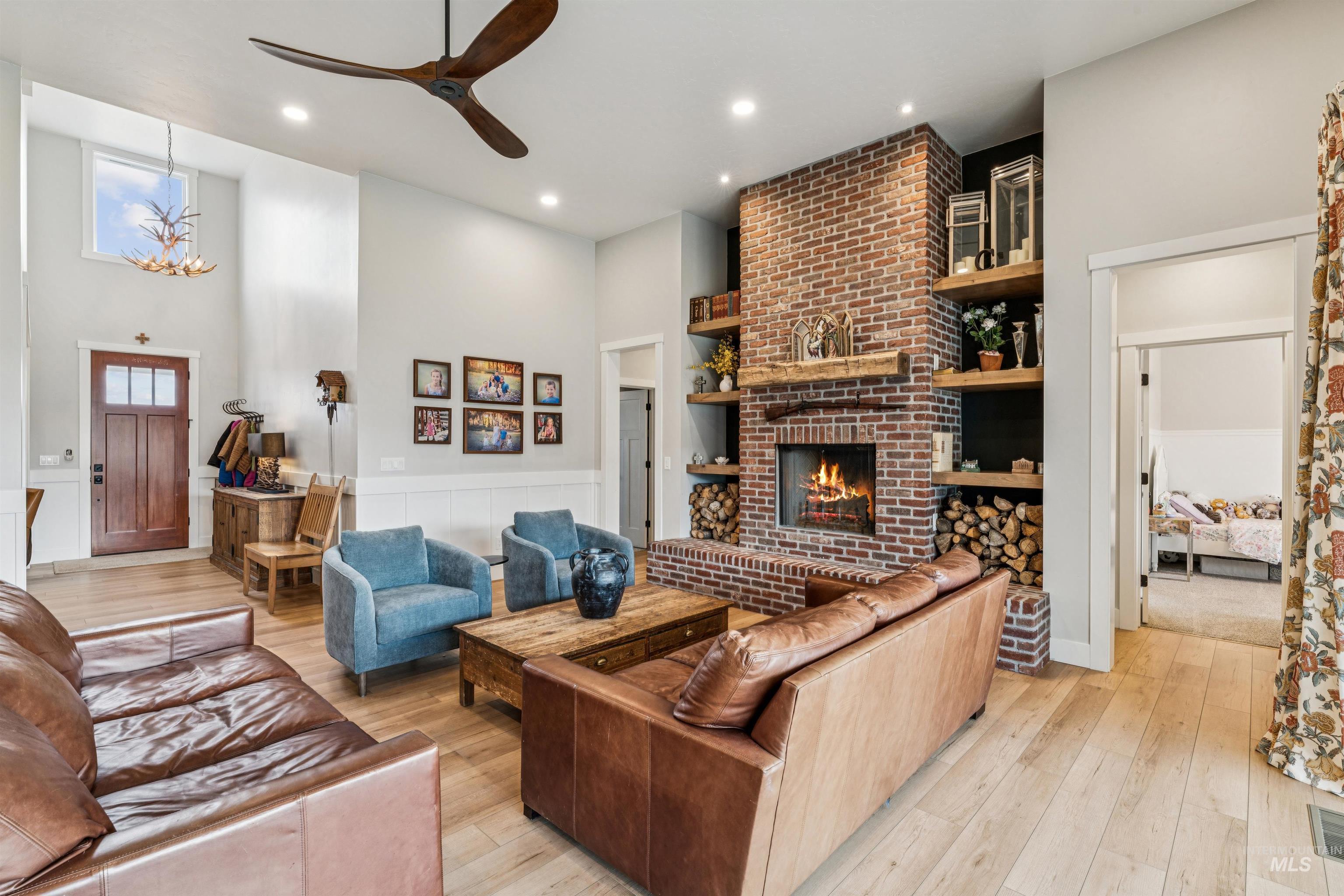 547 Bass Run Lane Marsing, ID 83639 - Photo 14 of 49 Living room featuring light wood-style flooring, a brick fireplace, ceiling fan, a high ceiling, and suspended lighting