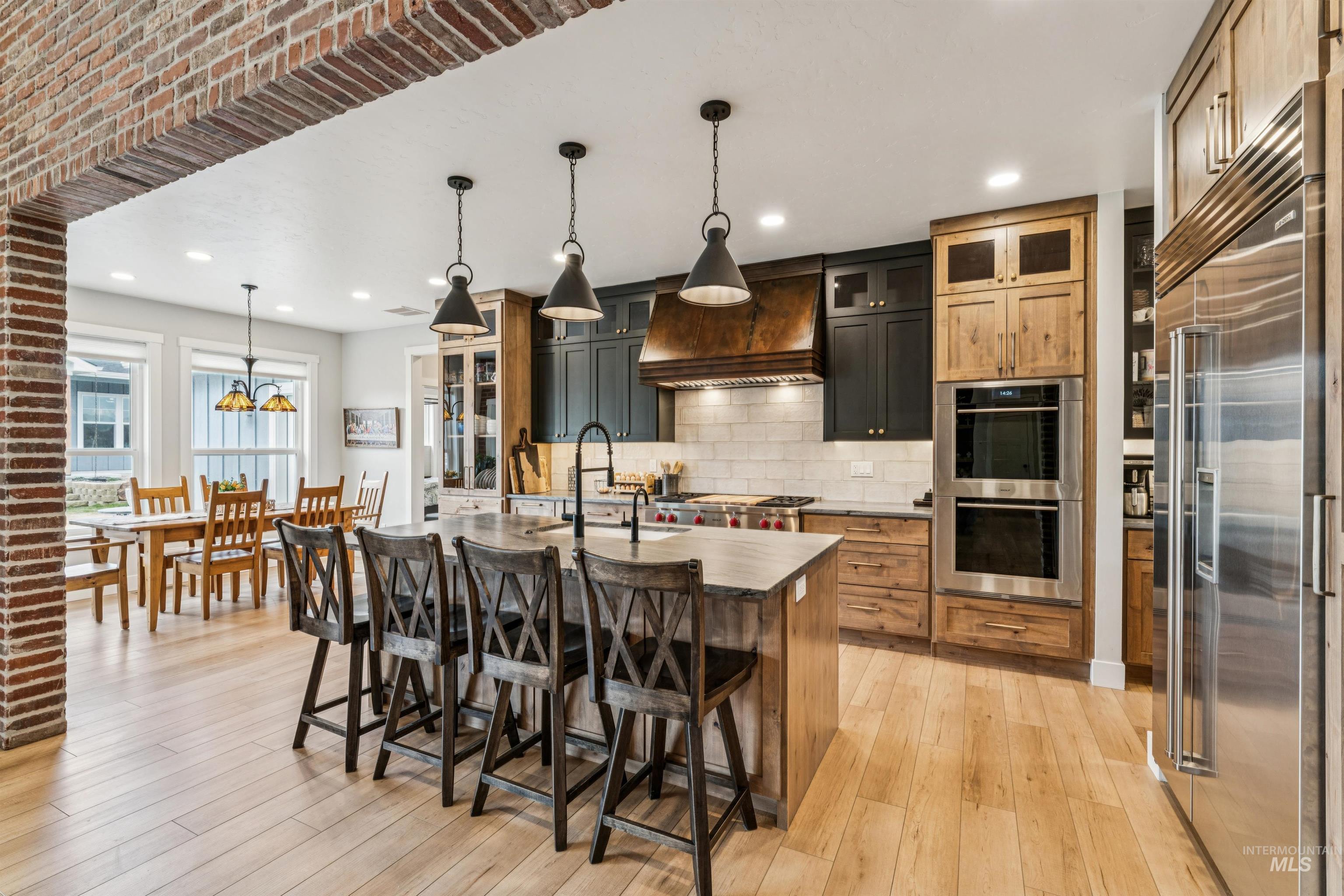 547 Bass Run Lane Marsing, ID 83639 - Photo 16 of 49 Kitchen with stainless steel appliances, glass fronted cabinets, a breakfast bar, an island with sink, and decorative light fixtures