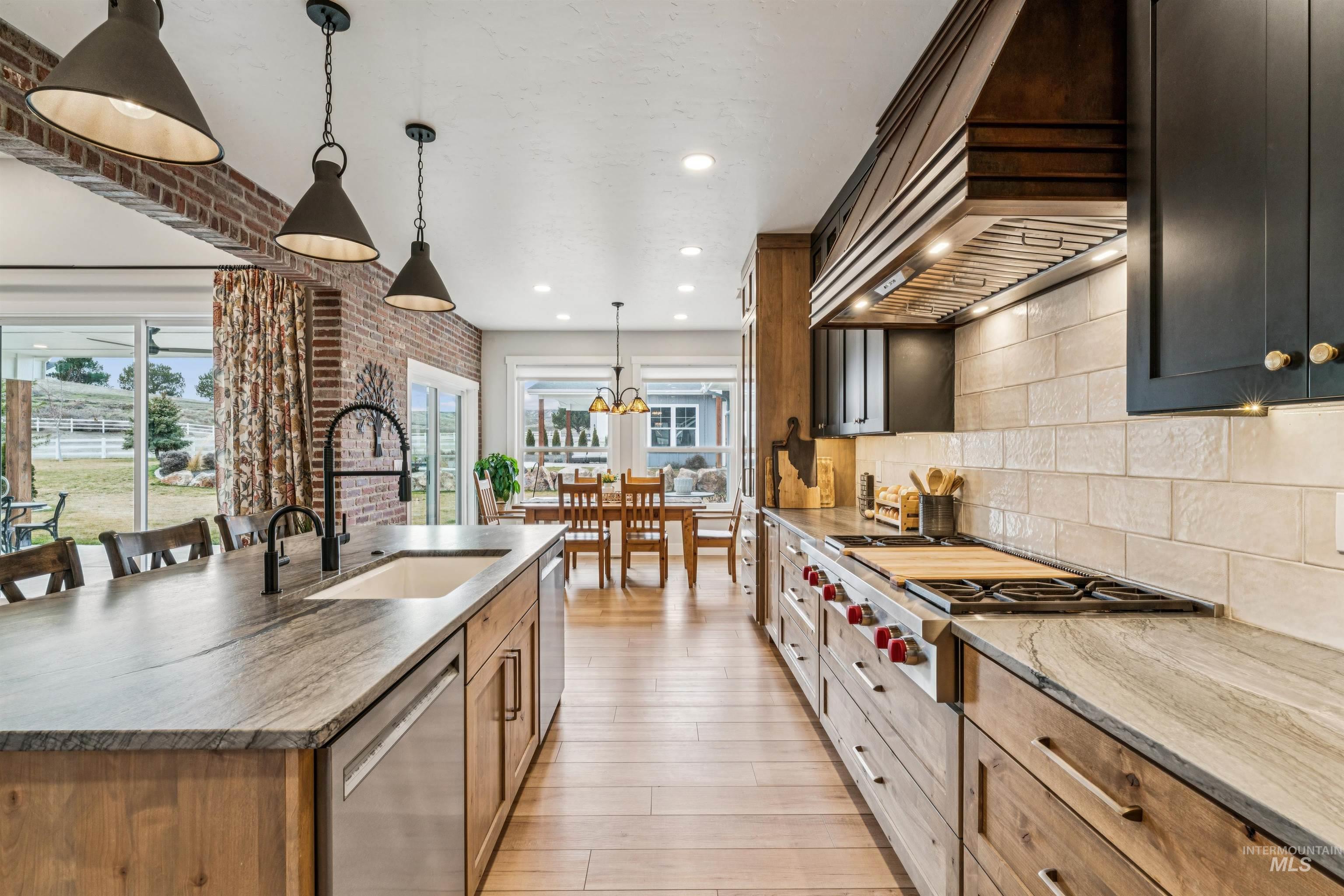 547 Bass Run Lane Marsing, ID 83639 - Photo 17 of 49 Kitchen with light stone countertops, pendant lighting, stainless steel appliances, light wood finished floors, and an island with sink