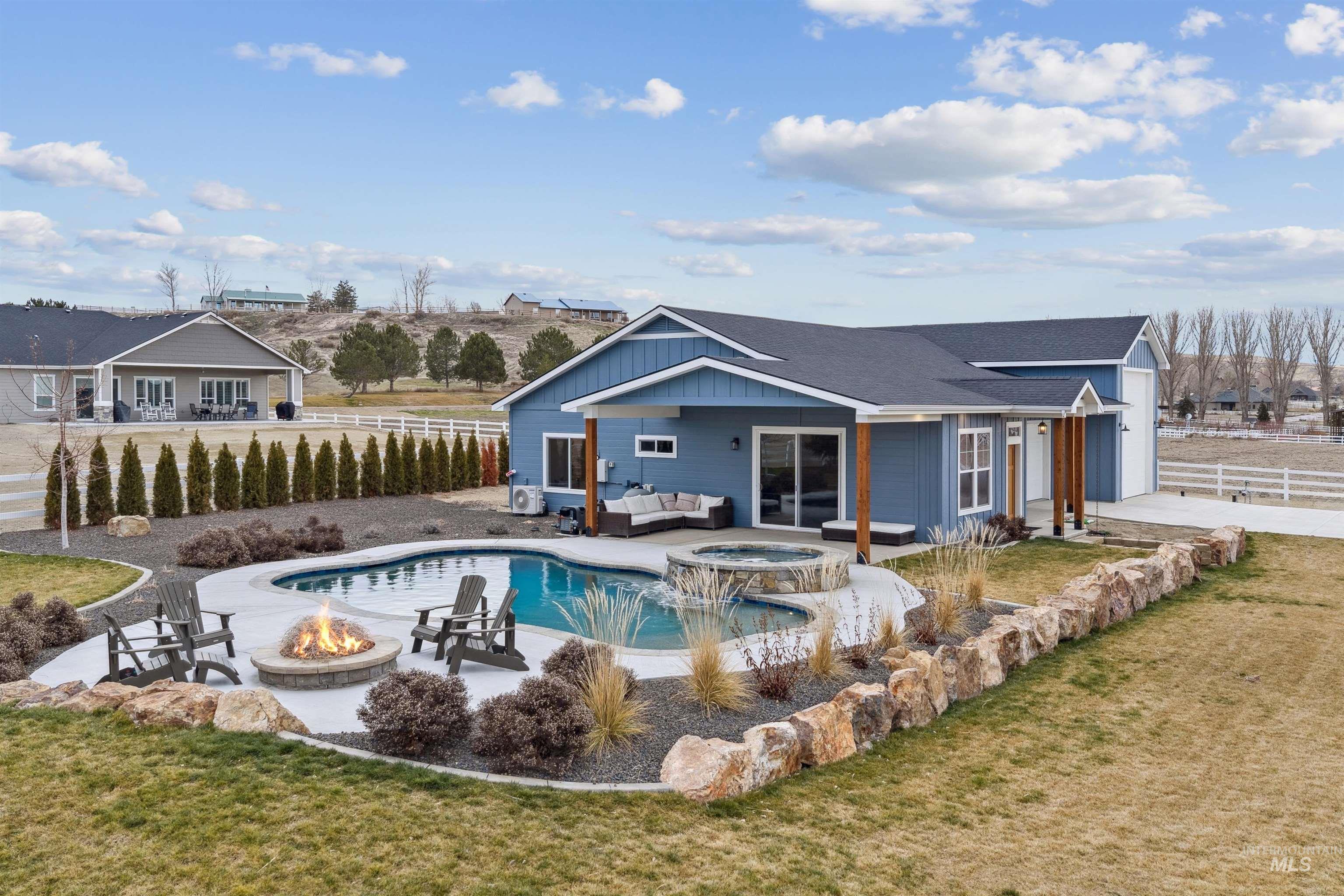 547 Bass Run Lane Marsing, ID 83639 - Photo 28 of 49 Rear view of house with a patio, an outdoor living space with a fire pit, board and batten siding, a pool with connected hot tub, and roof with shingles