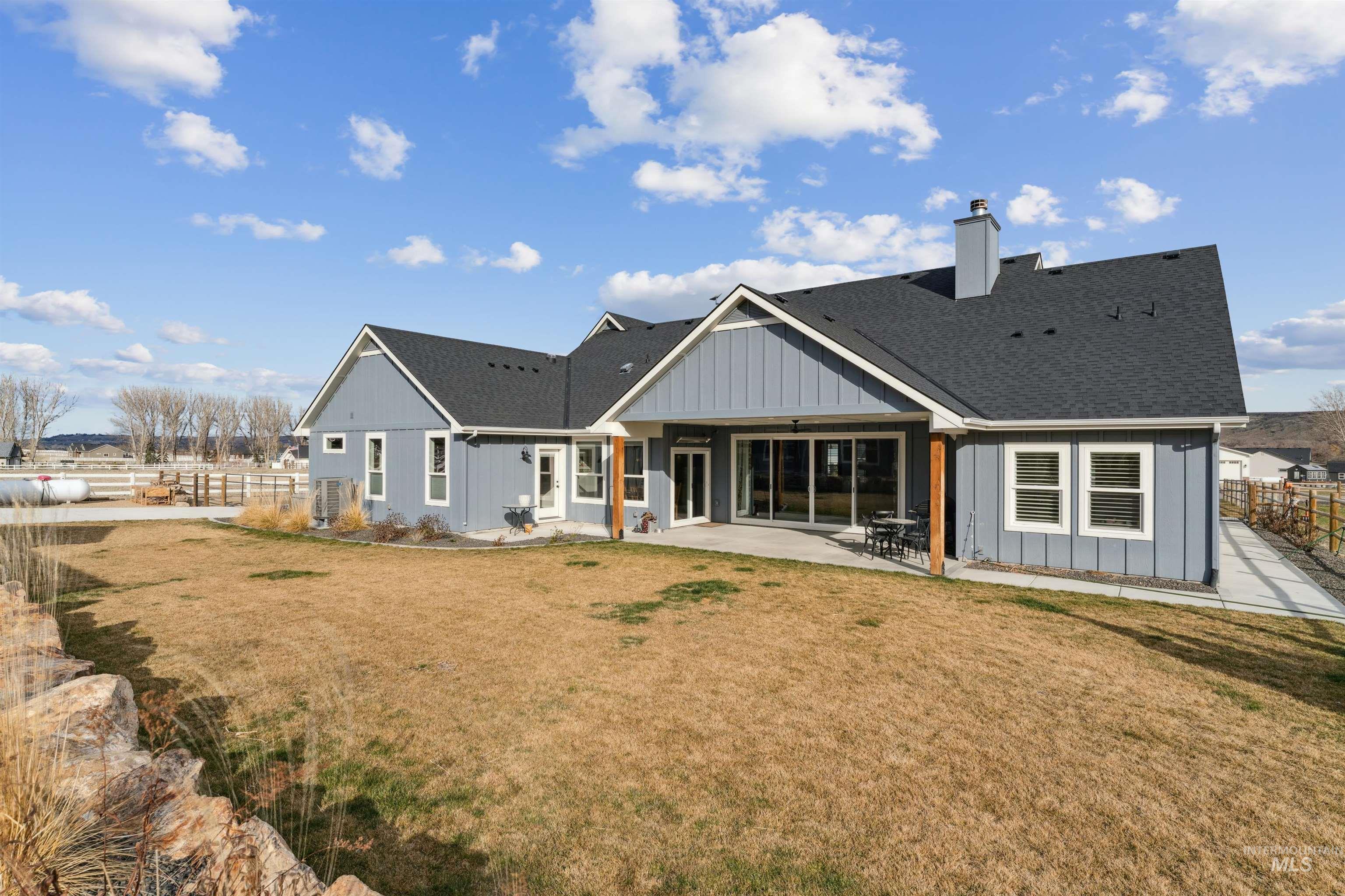 547 Bass Run Lane Marsing, ID 83639 - Photo 33 of 49 Back of house featuring a fenced backyard, a patio, a chimney, board and batten siding, and roof with shingles