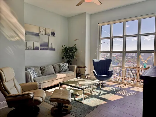 a living room with furniture a rug and a floor to ceiling window