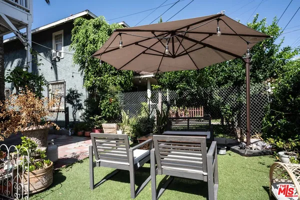 a backyard of a house with table and chairs under an umbrella
