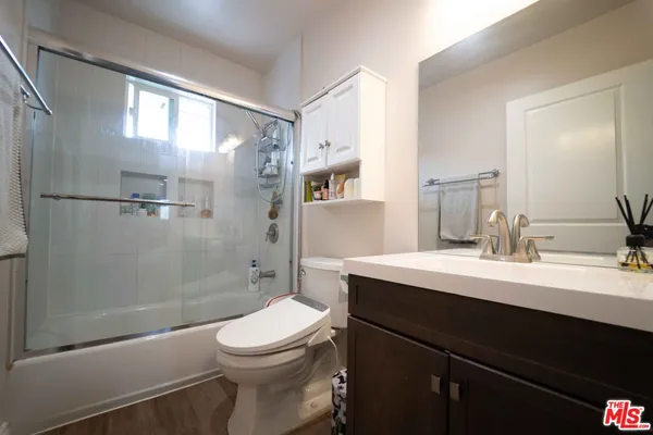 a bathroom with a sink a toilet a mirror and shower