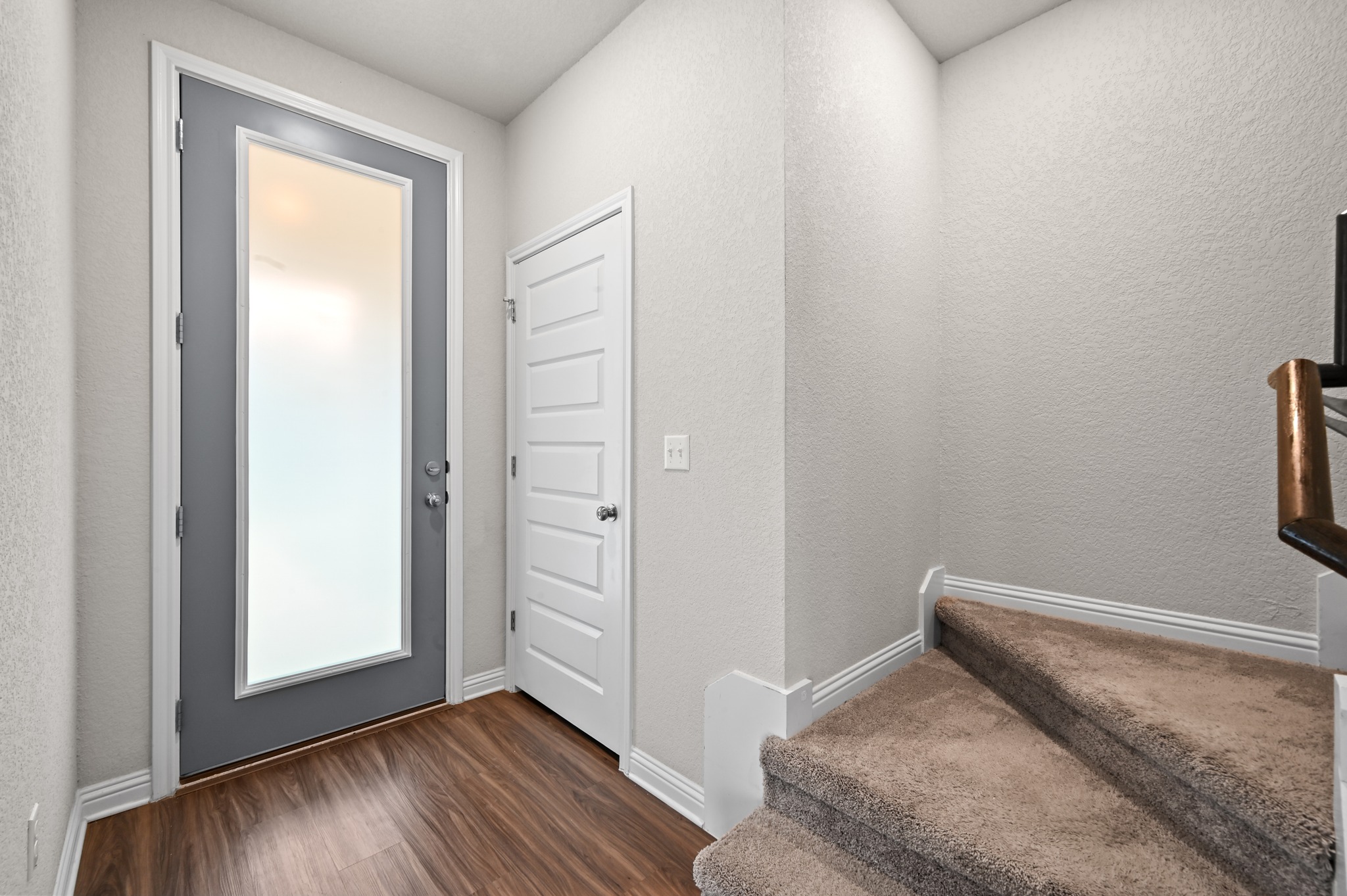 8201 Frida Bend Austin, TX 78744 - Photo 9 of 29 A well-illuminated entryway provides a warm welcome with rich wood-style flooring and carpeted stairs ascending to the next level.