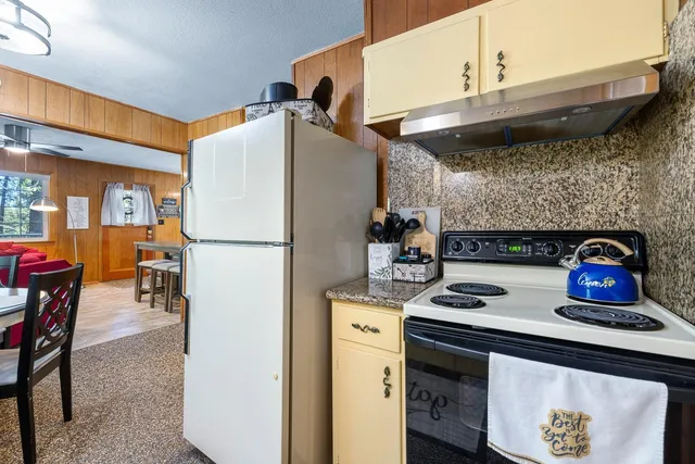 a kitchen with stainless steel appliances granite countertop a refrigerator a stove and a dining table