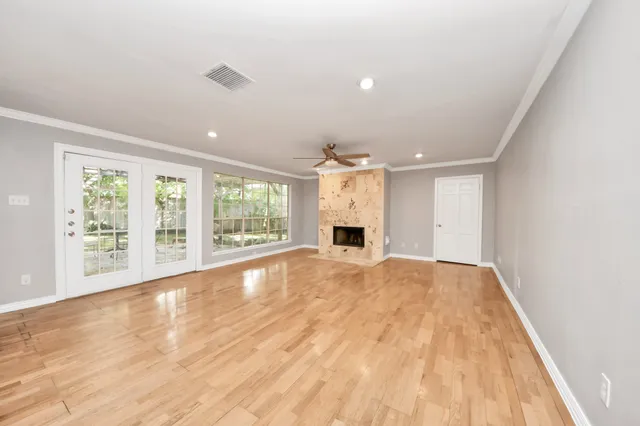 a view of an empty room with wooden floor and a kitchen