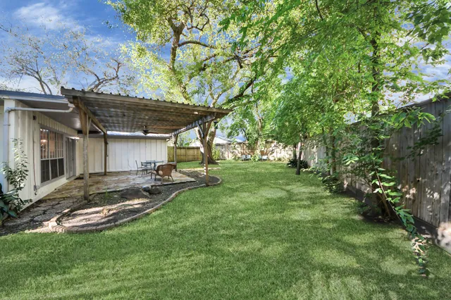 a view of a backyard with table and chairs and a large tree