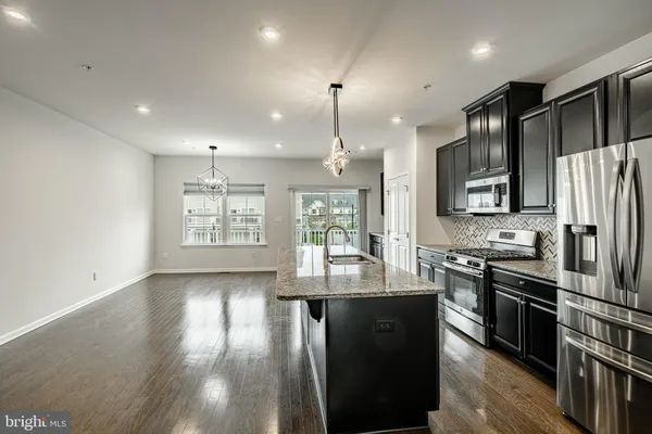a kitchen with stainless steel appliances granite countertop a refrigerator a stove a sink dishwasher and a oven with wooden floor