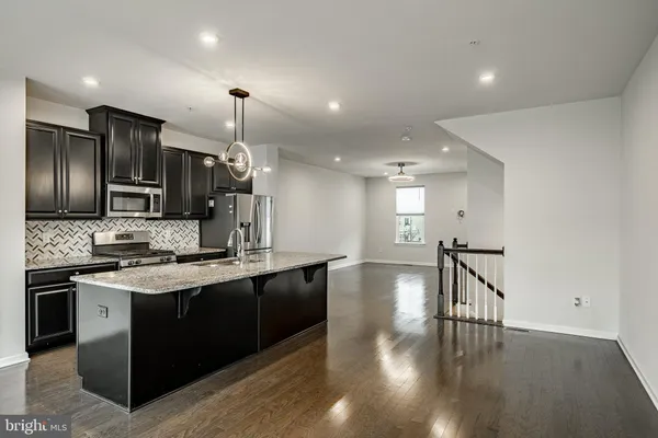 a kitchen with stainless steel appliances granite countertop a sink a stove and a wooden floors