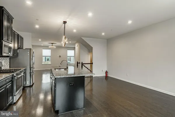 a dining room with kitchen island stainless steel appliances furniture a fireplace and a chandelier