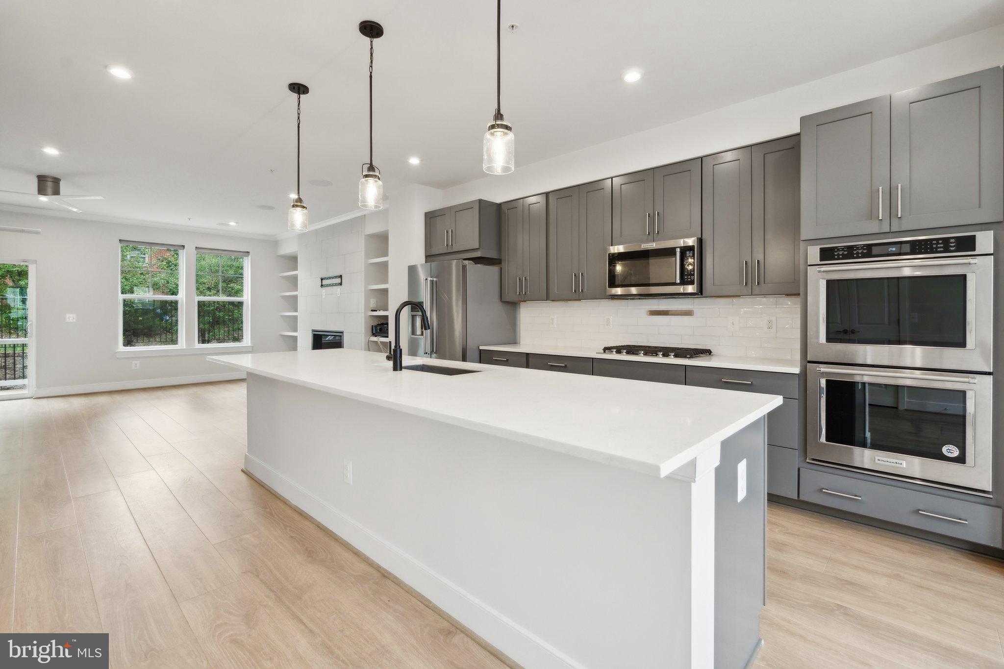 3034 Declan Way Falls Church, VA 22044 - Photo 5 of 41 a kitchen with kitchen island a stove a sink a microwave a refrigerator and a wooden floor