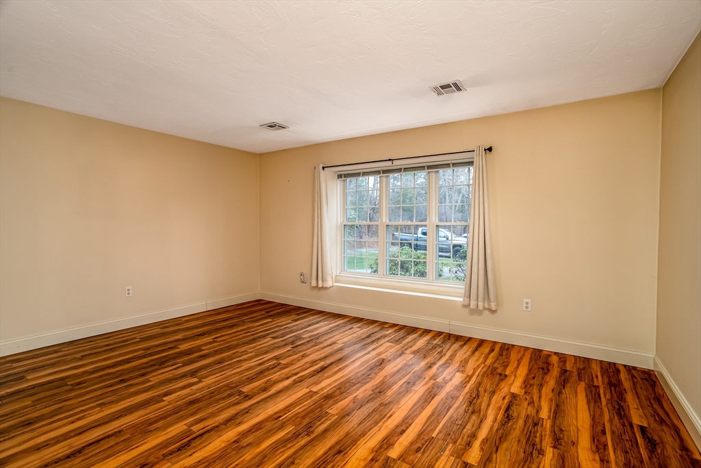 115 Ridgefield Circle, Unit D Clinton, MA 01510 - Photo 14 of 29 a view of an empty room with wooden floor and a window