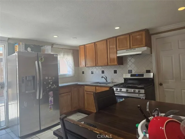 a kitchen with stainless steel appliances granite countertop a refrigerator sink and stove