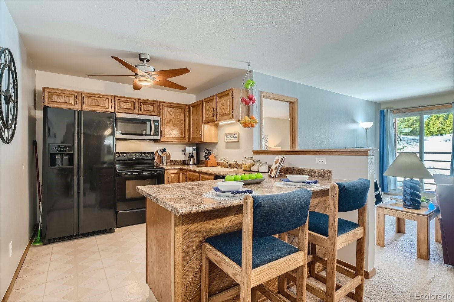 a kitchen with stainless steel appliances granite countertop a refrigerator a stove a sink a dining table and chairs