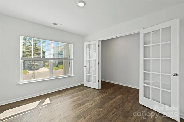 an empty room with wooden floor and windows