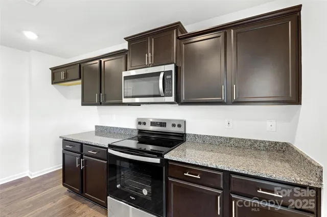 a kitchen with granite countertop a stove microwave and sink