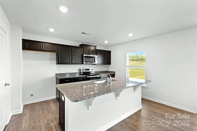 a kitchen with a sink a stove a microwave a counter top space and cabinets