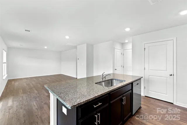 a kitchen with granite countertop kitchen island a sink stainless steel appliances and white cabinets