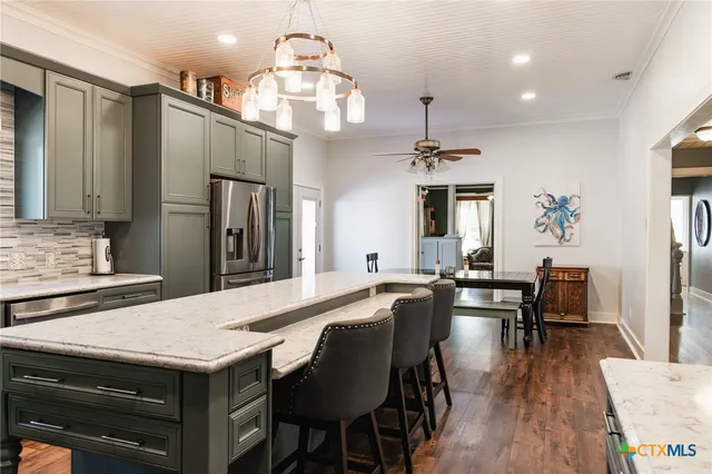 a kitchen with granite countertop a stove a sink a dining table and chairs