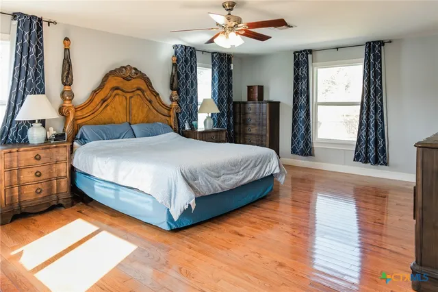 a bedroom with a bed and dresser with wooden floor