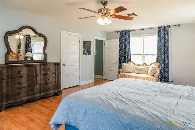 a bedroom with a bed a dresser and wooden floor