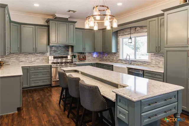 a kitchen with a stove a sink dishwasher a kitchen island with wooden cabinets and floor