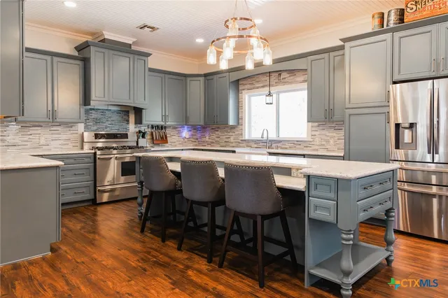 a kitchen with stainless steel appliances granite countertop a table chairs sink refrigerator and cabinets