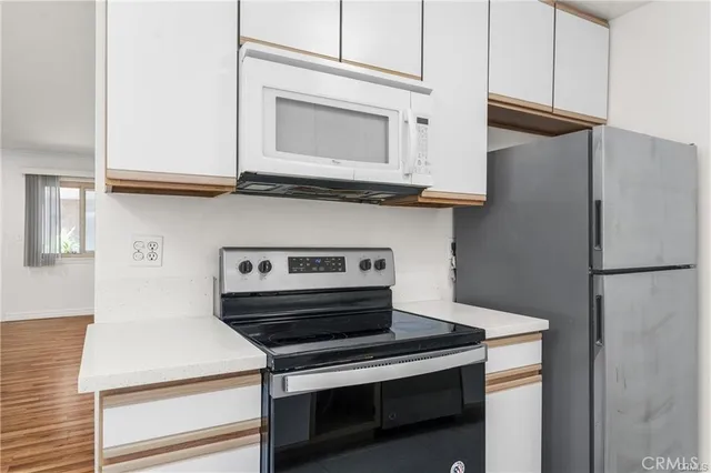 a kitchen with stainless steel appliances granite countertop white cabinets and a wooden floor