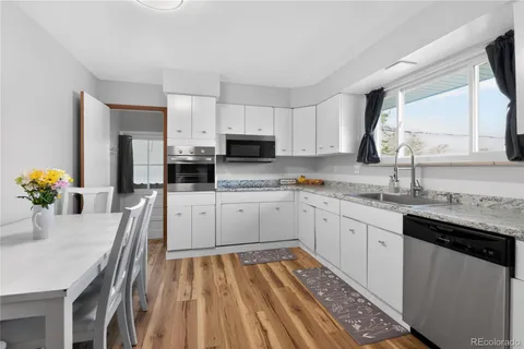 a kitchen with stainless steel appliances granite countertop a sink dishwasher a microwave oven and a dining table with wooden floor