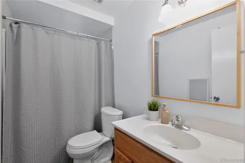 a bathroom with a sink a toilet a mirror and shower curtain