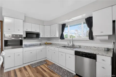 a kitchen with granite countertop white cabinets and white appliances