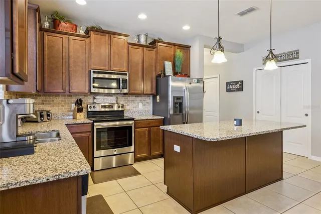 a kitchen with stainless steel appliances kitchen island a table chairs in it and wooden floors