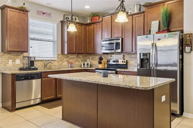 a kitchen with stainless steel appliances granite countertop a sink a stove and a refrigerator