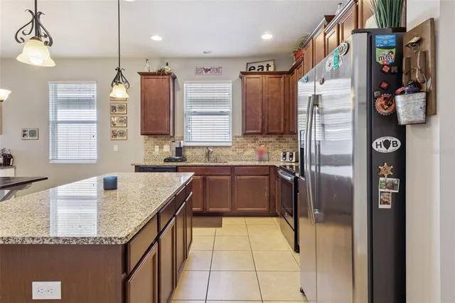 a kitchen with kitchen island granite countertop a stove a sink a refrigerator a oven a dining table and chairs