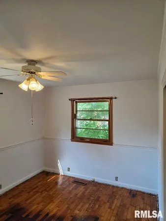 an empty room with a window and chandelier fan