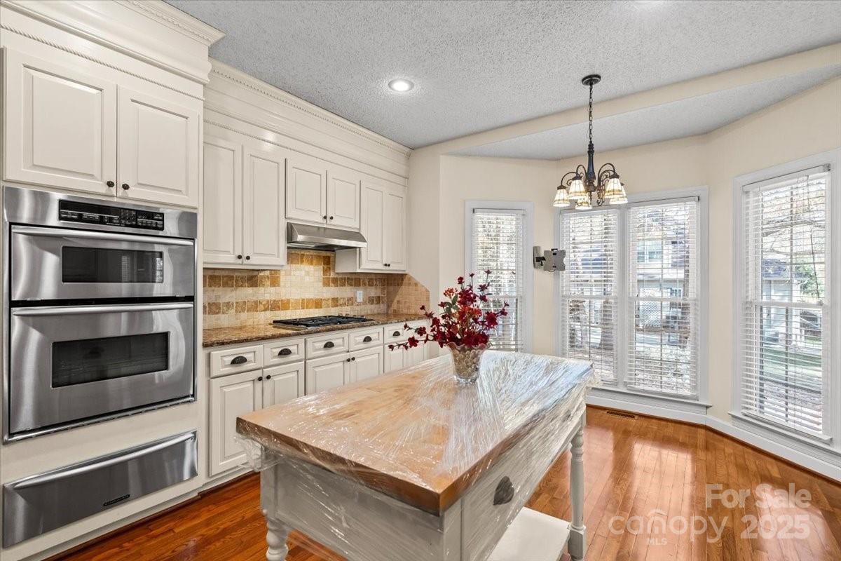 5619 Weddington Road Concord, NC 28027 - Photo 17 of 48 a kitchen with kitchen island granite countertop a stove a counter space a sink cabinets and appliances