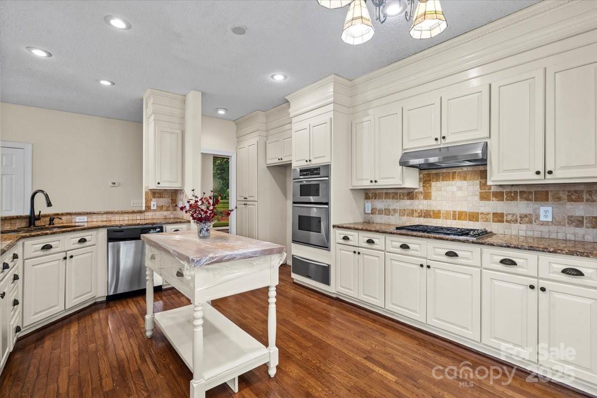 5619 Weddington Road Concord, NC 28027 - Photo 18 of 48 a kitchen with granite countertop a sink stainless steel appliances and white cabinets