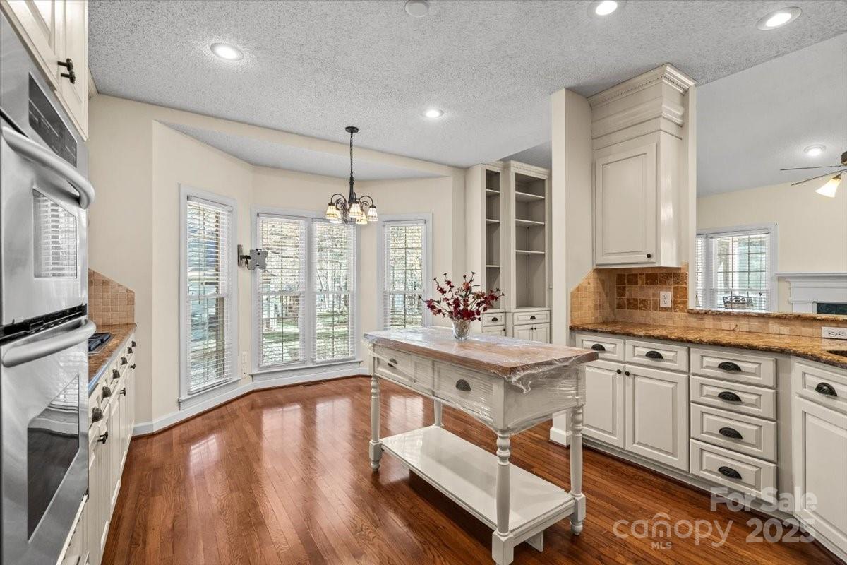 5619 Weddington Road Concord, NC 28027 - Photo 19 of 48 a large white kitchen with stainless steel appliances granite countertop a stove a sink dishwasher and white cabinets with wooden floor