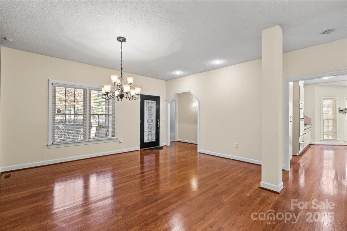5619 Weddington Road Concord, NC 28027 - Photo 7 of 48 a view of an empty room with wooden floor and a chandelier