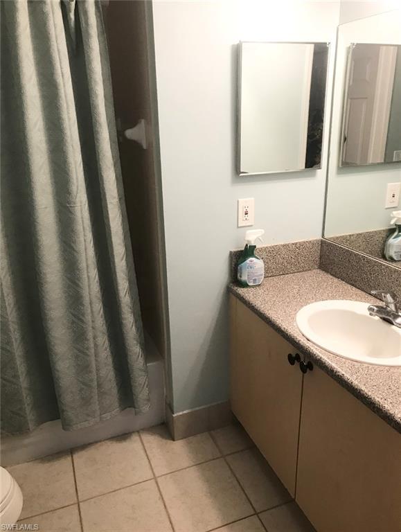 1115 Reserve Court, Unit 2 Naples, FL 34105 - Photo 2 of 2 Bathroom vanity with an integrated sink, speckled countertop, and wood-finish cabinetry