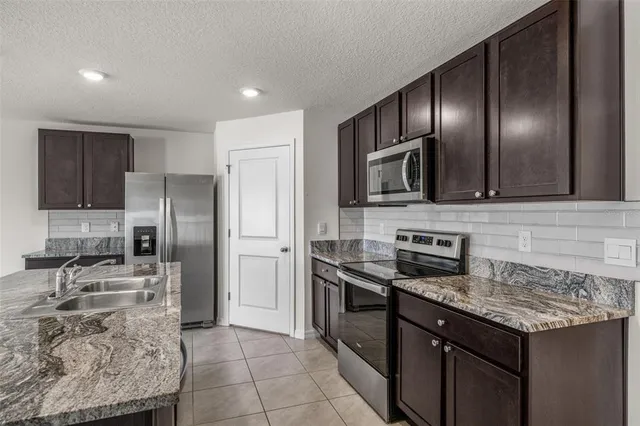 a kitchen with stainless steel appliances granite countertop a stove microwave and refrigerator