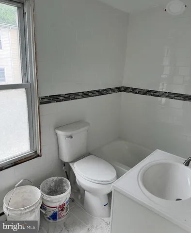 a white toilet sitting next to a bathroom sink and a window