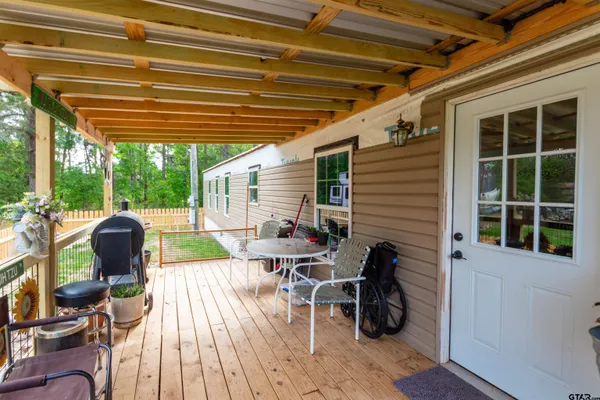 a view of a patio with table and chairs with wooden floor and fence