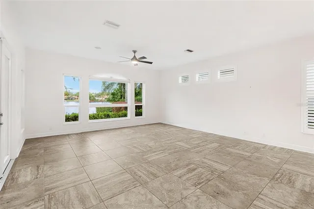 a view of an empty room with a chandelier fan and kitchen view