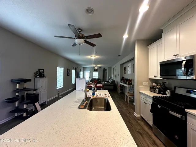 a large white kitchen with sink stove microwave and refrigerator