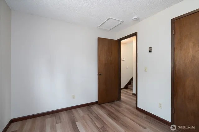 a view of an empty room with wooden floor and closet