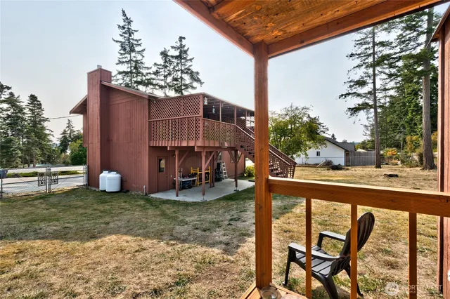 a view of a chair and table in the balcony next to a yard
