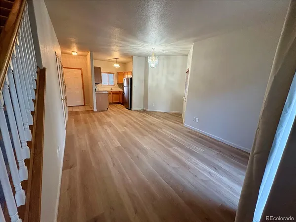 a view of empty room with wooden floor and door