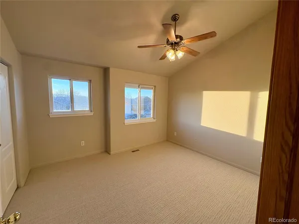 an empty room with windows and fan
